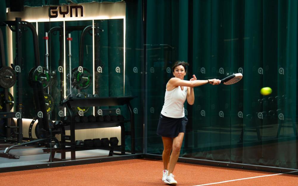 Player in action on an indoor padel court lined with acoustic curtains at Performance Padel