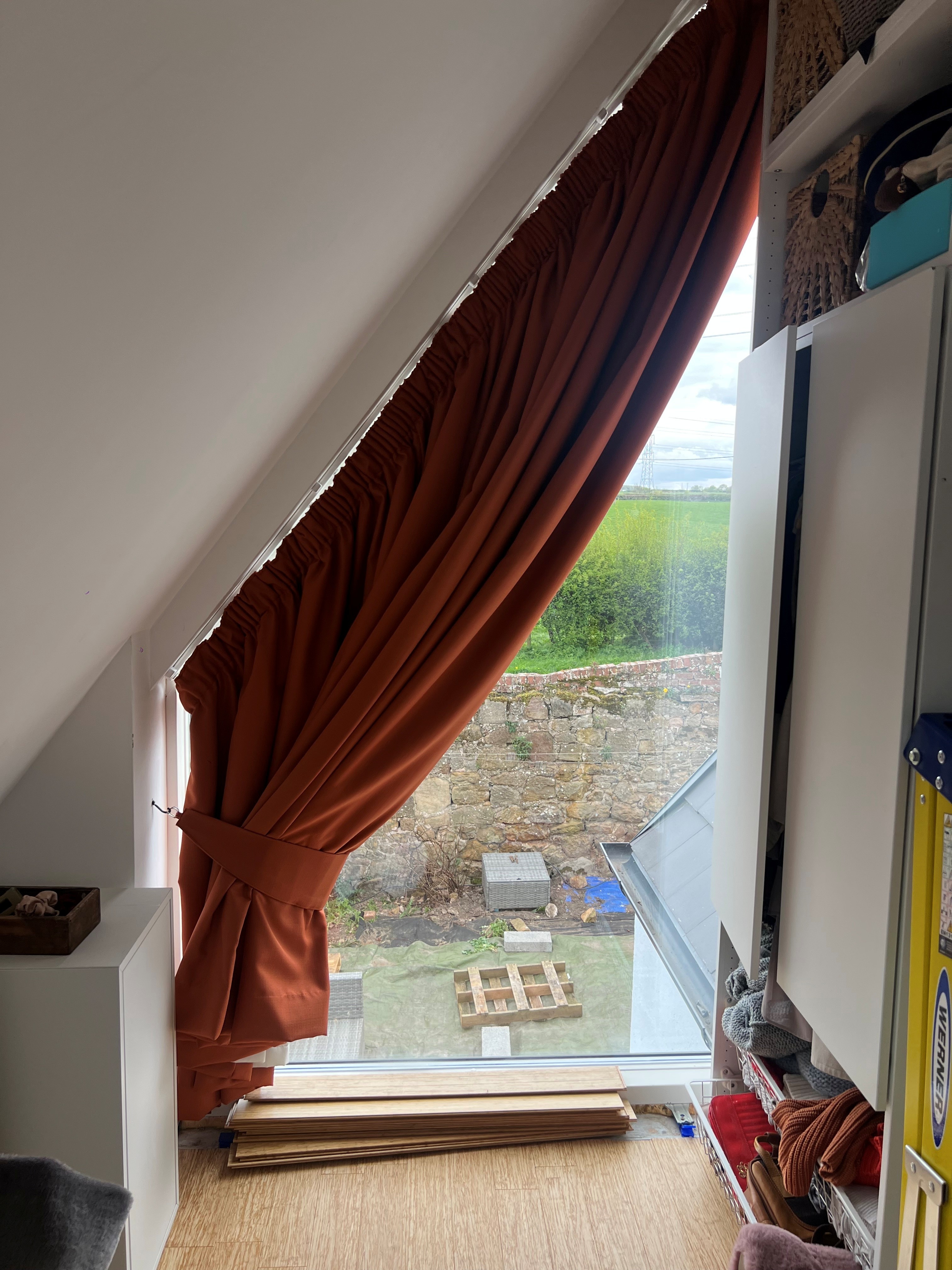 Sloped window curtain tied back to open up the view in a loft room